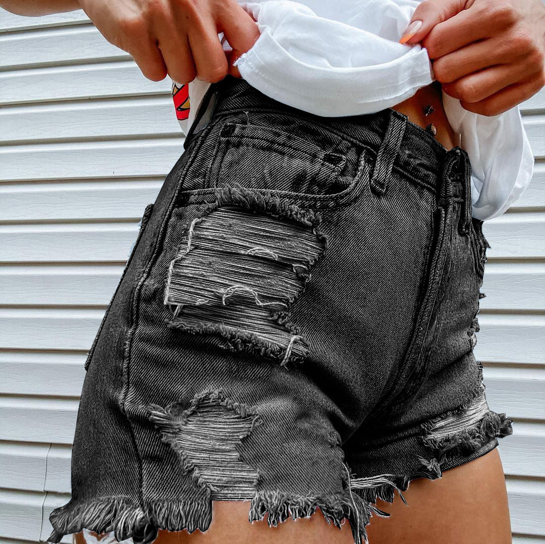 Person in schwarzen Jeansshorts mit farbenfrohem Taschenmuster vor neutralem Hintergrund