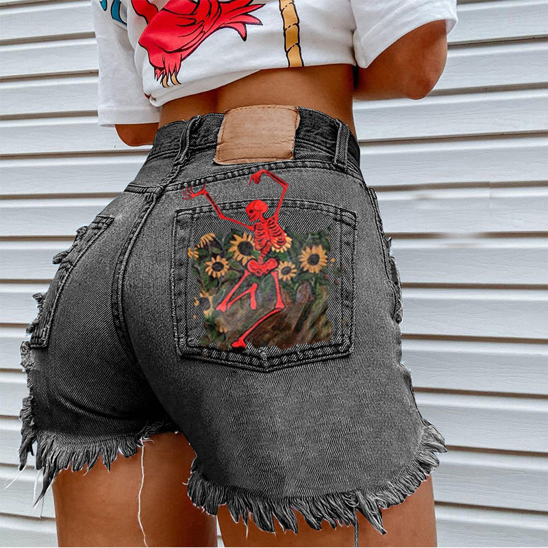 Person in schwarzen Jeansshorts mit farbenfrohem Taschenmuster vor neutralem Hintergrund